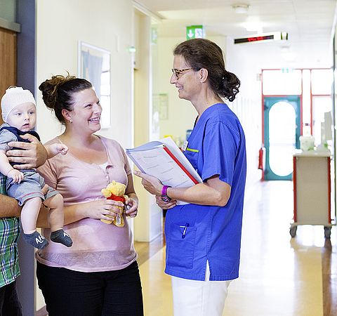 Mutter mit Kind auf dem Arm und Krankenschwester